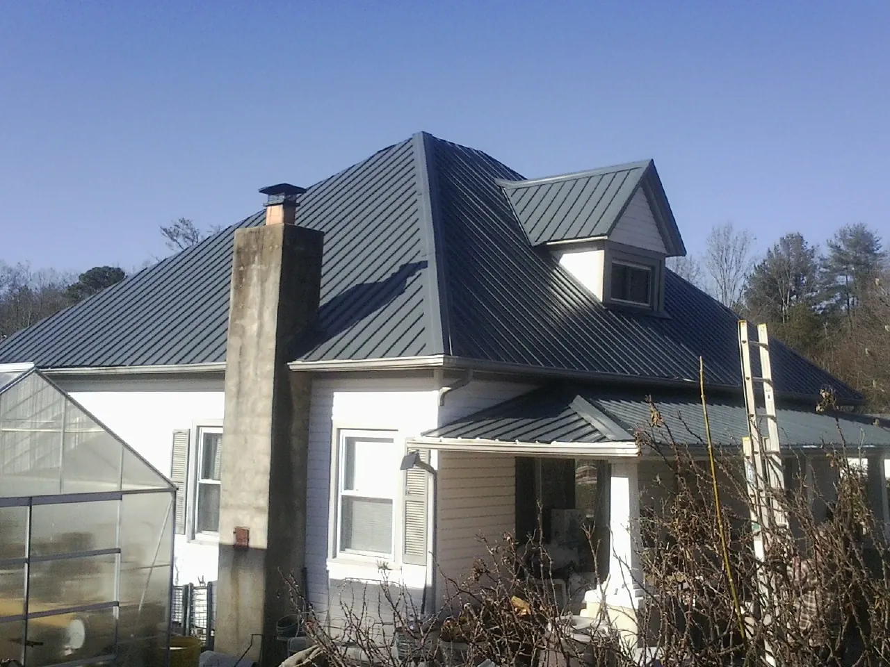 Dark blue standing seam metal roof on a white farmhouse with dormer — Slate & Tile Roof Repair by Roofing Brothers in Normal