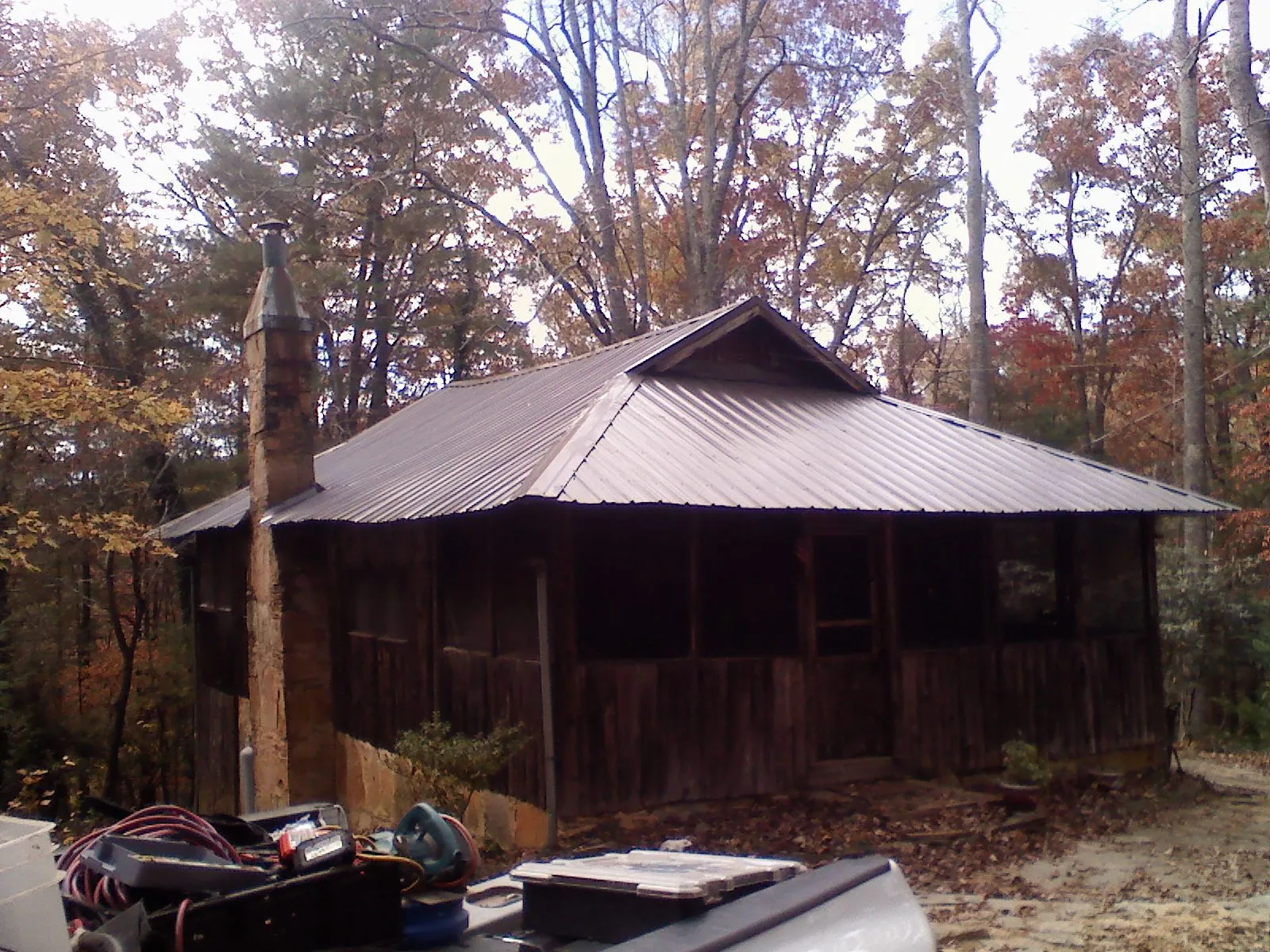 Brown metal hip roof on an old cabin with a stone chimney in Normal