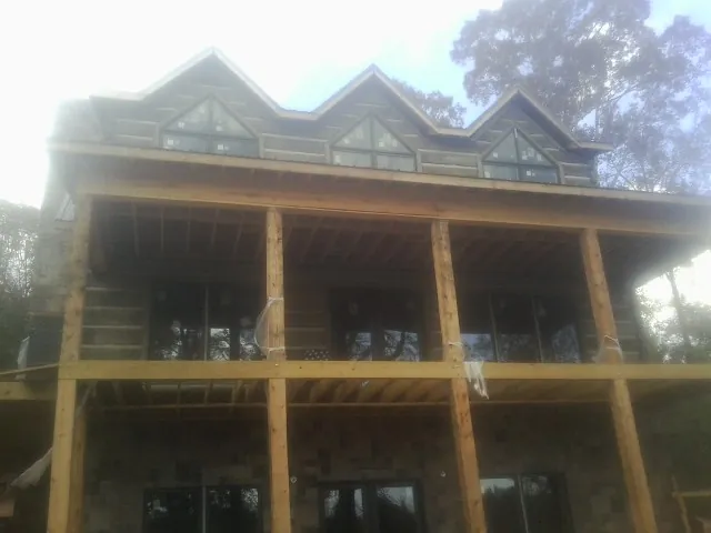 Dormers and porch framing on a large log home under construction — Roof Coating work by our crew in Normal