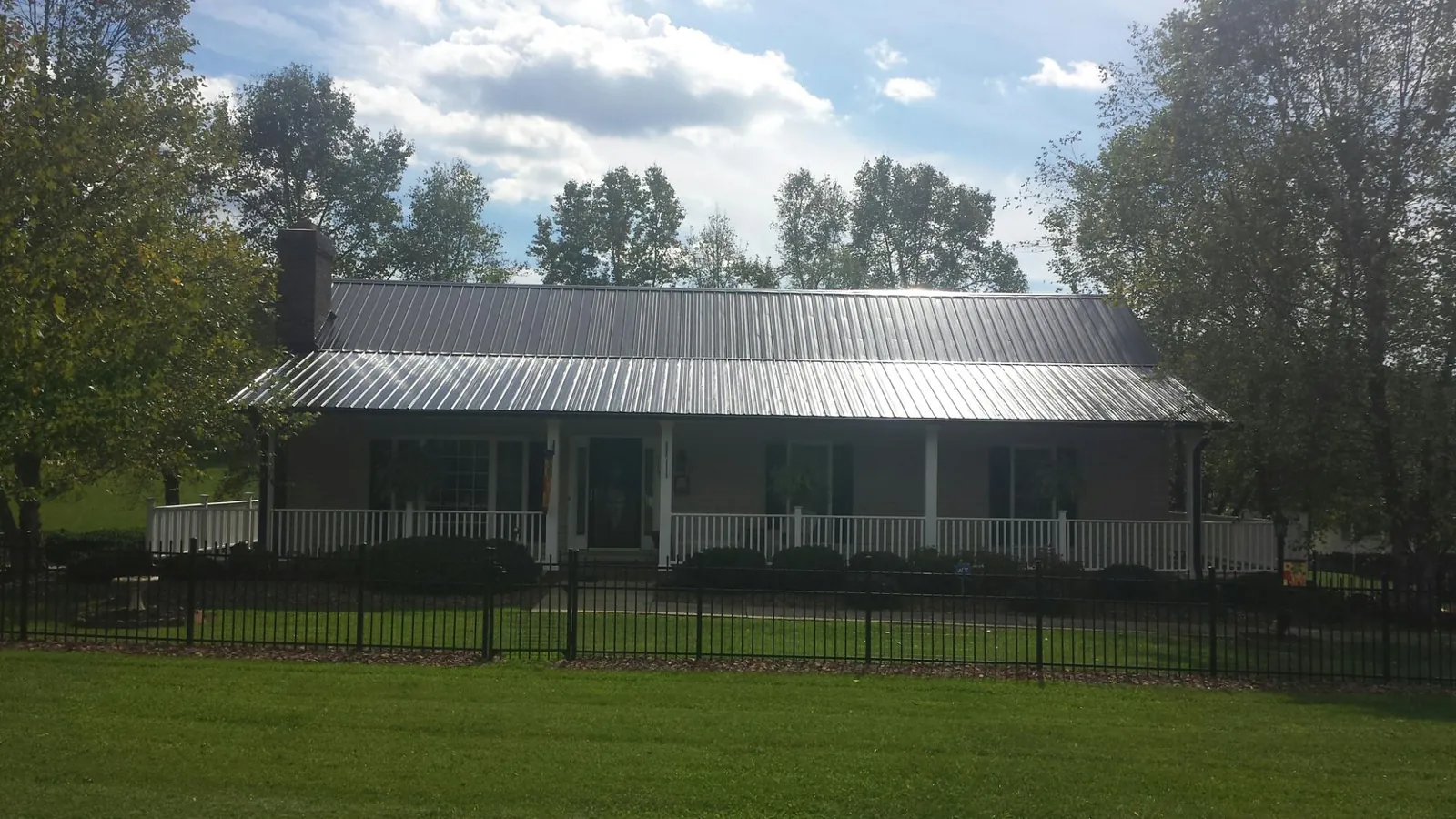Gray metal roof on a brick ranch with a full width front porch — Gutter Guard Installation work by our crew in Normal