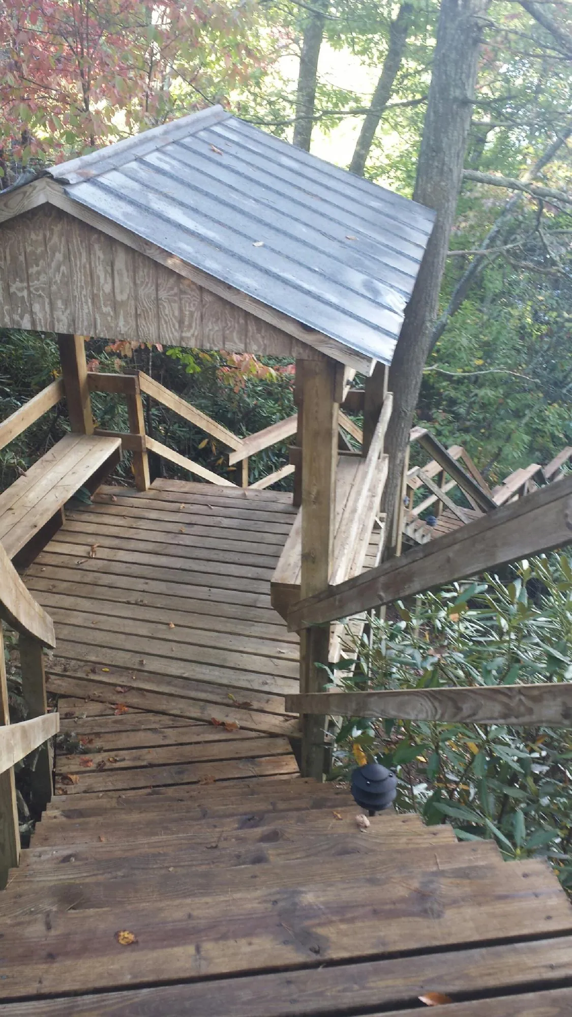 Metal roofed shelter over wooden steps on a wooded walkway — Skylight Repair & Installation work by our crew in Normal