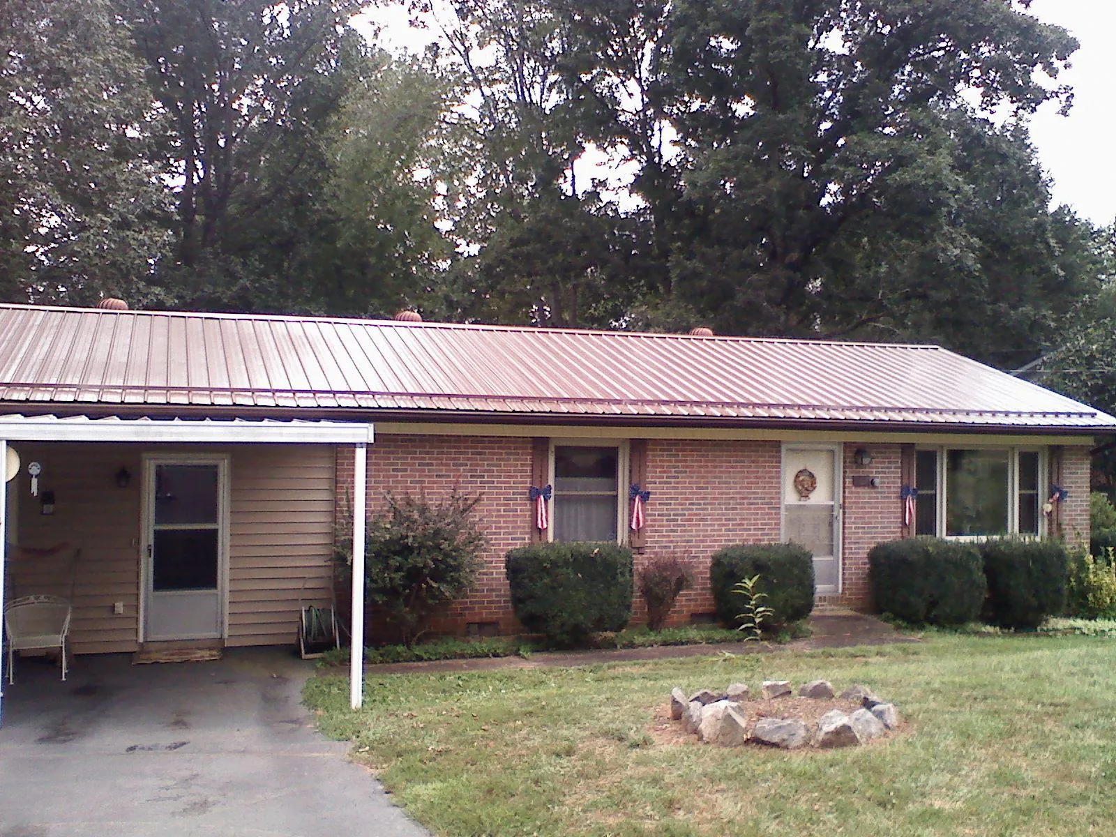 Bronze metal roof and carport on a brick ranch home — Roof Repair work by our crew in Normal